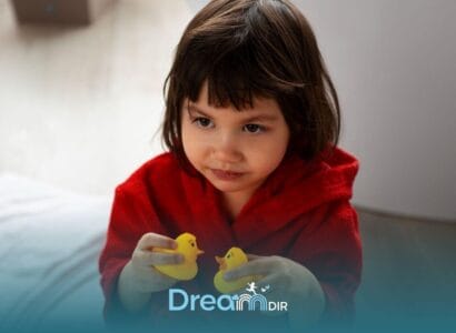 Autistic girl in red robe holding two toy ducks, showing focused and thoughtful expression during independent play time