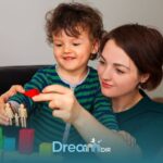 Therapist and autistic child playing with colorful blocks and shapes together, showing supportive learning and interaction at home