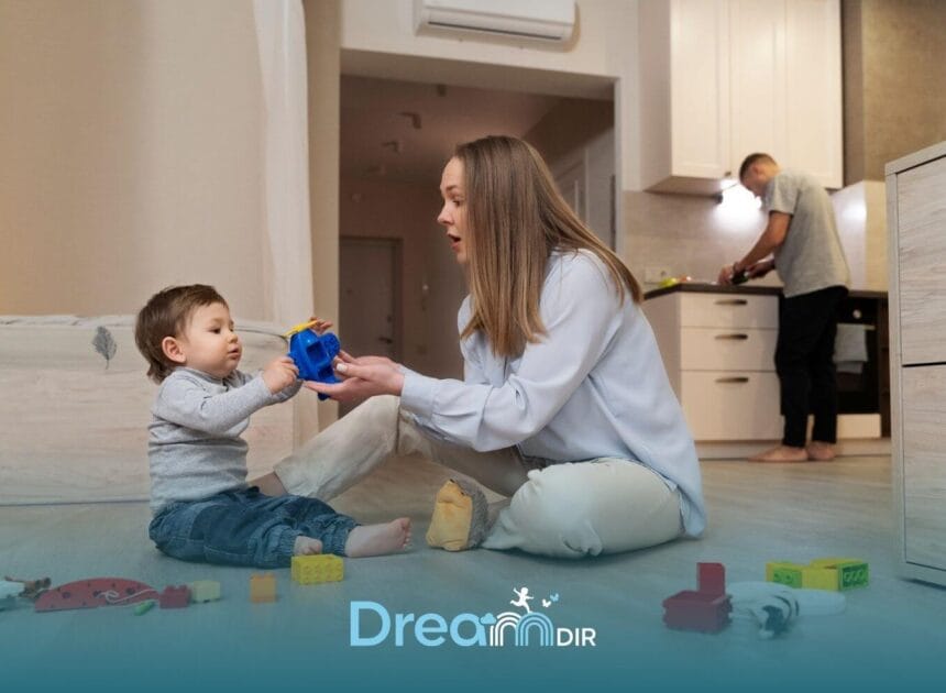 Therapist interacting with autistic toddler on the floor using a toy helicopter while another parent prepares food