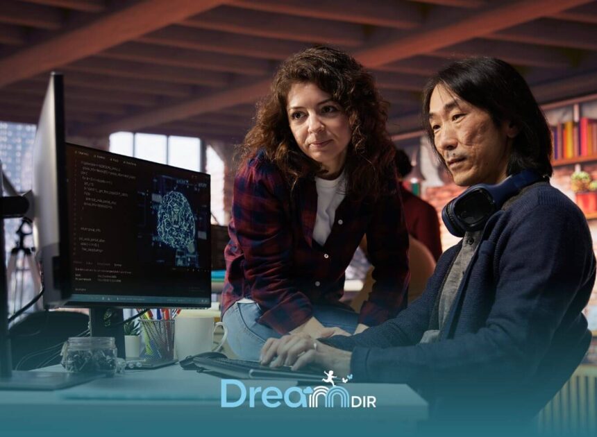 Two therapist collaborating at desk reviewing code and data on computer screen during hands-on technical training session