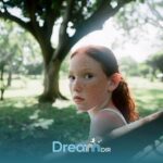 Autistic girl with freckles sitting on park bench, looking reflective in nature, representing emotional awareness.