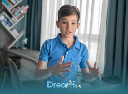 Autistic boy gesturing with hands while speaking indoors, illustrating communication skills and possible speech development.