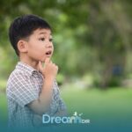 Thoughtful autistic boy outdoors touching chin while observing surroundings, representing curiosity and cognitive development