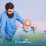Therapist assisting autistic old man at laptop, pointing at screen while offering guidance and support