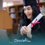 ABA graduate in cap and gown holding diploma while attending virtual ceremony on laptop in a quiet indoor setting