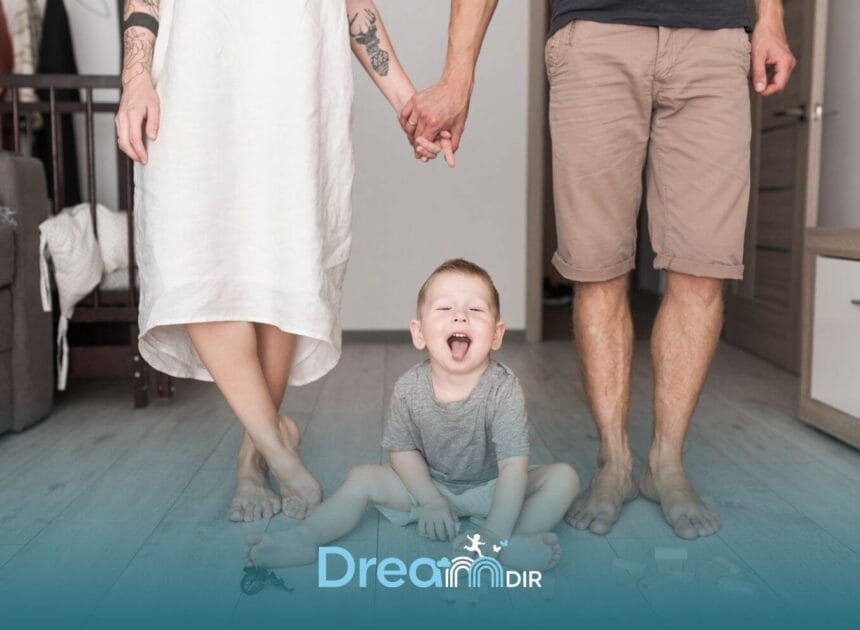 Therapists holding hands behind an autistic toddler sitting on the floor with toys, representing support & safety