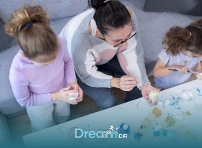 Therapist & two autistic children painting decorative eggs together at a table, promoting creativity & bonding