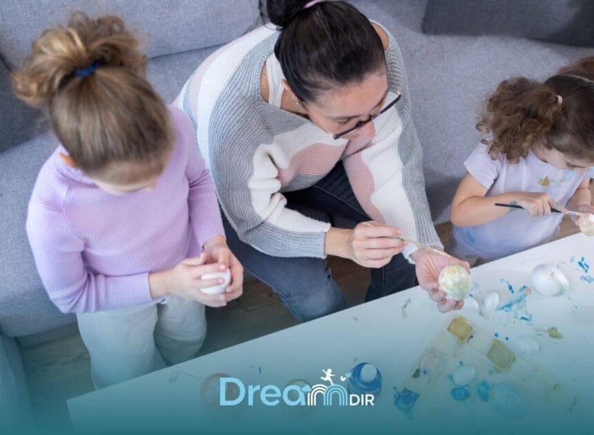 Therapist & two autistic children painting decorative eggs together at a table, promoting creativity & bonding